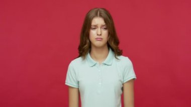 Dramatik bir ağlama. Polo tişörtlü, üzgün, başı öne eğik, ağlayan, yüzünü saklayan, çaresiz ve sorunlar konusunda çaresiz hisseden genç bir kadın. Kırmızı arkaplanda izole edilmiş kapalı stüdyo çekimi