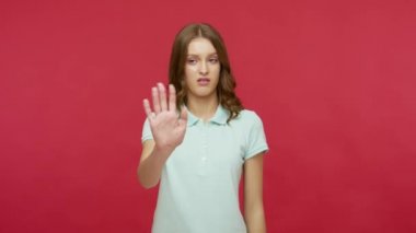 İzlemek istemiyorum! Polo tişörtlü, gözlerini kapayan ve el kol hareketi yapan, utangaç ve utangaç genç esmer kadın utangaç içeriğe bakmaya çekiniyor. Kırmızı arkaplanda izole edilmiş kapalı stüdyo çekimi