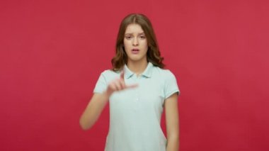 Kaybettim, başarısızlığımı. Polo tişörtlü genç esmer kadın ezik jestler yapıyor, başında L işareti var ve hayal kırıklığıyla bakıyor, yenilgi yüzünden depresyonda, başarısız. Kapalı stüdyo çekimi, izole.