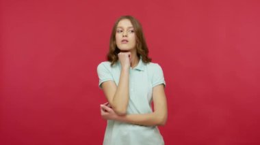 Polo tişörtlü, sıkılmış, ilgisiz bir ifadeyle kameraya bakan sıkıcı konuşmalardan ve neredeyse uyumaktan bıkmış genç bir kadın. Kırmızı arkaplanda izole edilmiş kapalı stüdyo çekimi