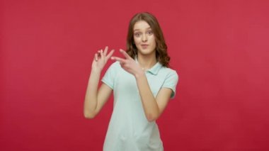 Polo tişörtlü neşeli, iyimser genç kadın hashtag 'ini gösteriyor ve gülüyor, el hareketleriyle eğleniyor, viral web içeriğini etiketliyor. Kırmızı arkaplanda izole edilmiş kapalı stüdyo çekimi