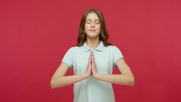 内心的平静和沉思 穿着T恤衫的积极镇定的年轻女性保持双手的姿势 休息和集中精神 做瑜伽呼吸练习 在红色背景下隔离的工作室拍摄 — 图库视频影像