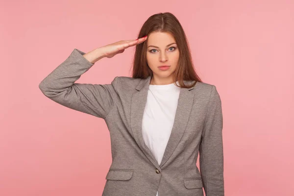 ビジネススーツの深刻なスマート若い女性の肖像敬礼を与え 注文に耳を傾け 責任ある気配りの表現を探している ピンクの背景に隔離されたスタジオショット — ストック写真