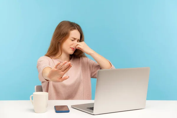 臭いがする 職場でノートパソコンを持っている若い女性従業員を混乱させ 息を保持し ひどい悪臭を避けるために彼女の鼻をつまんで ジェスチャーを停止します 青い背景に隔離された屋内スタジオで — ストック写真