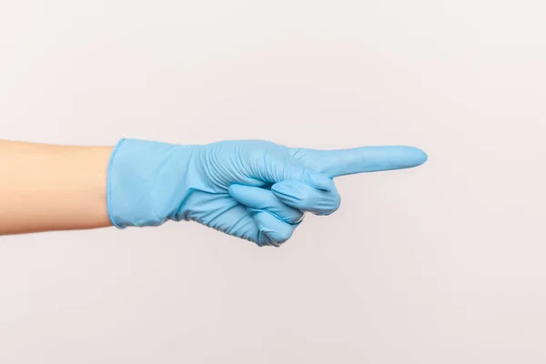 プロフィール側のビューの青い外科手袋を示すか 指で何かを指して 人間の手の閉鎖 屋内スタジオ撮影灰色の背景に隔離された — ストック写真