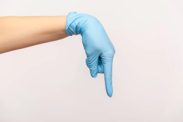 プロフィール側のビューを表示するか 指で下を指す青い外科用手袋で人間の手のクローズアップ 屋内スタジオ撮影灰色の背景に隔離された — ストック写真