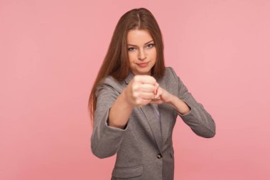 İş elbisesi içindeki cesur, kendinden emin genç bir kadının portresi yumruk yumruğa, boks kameraya, mücadele kavramı, kavga ve nefsi müdafaa. Pembe arka planda kapalı stüdyo çekimleri