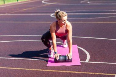 Yazın paspasın üzerinde kararlı, formda bir kadın antrenmanı, köpük silindirli karın kasları egzersizi, diz egzersizi. Spor aktivitesinden önce ısınma, sağlık konsepti