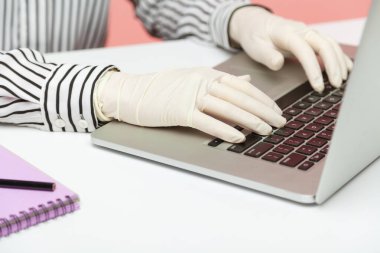 Kapalı ofis çalışanı hijyenik eldivenler veriyor klavyede yazıyor, karantina sırasında dizüstü bilgisayarda çalışıyor. Koronavirüsün yayılmasını önlemek için kendini izole etmek. İç mekan, stüdyo çekimi