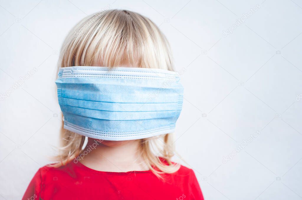 Small Girl with face hidden under surgical mask as a virus protection.