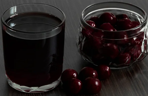 Bir bardak kiraz suyu ve kiraz suyu için. Siyah arka planda kiraz suyu için.