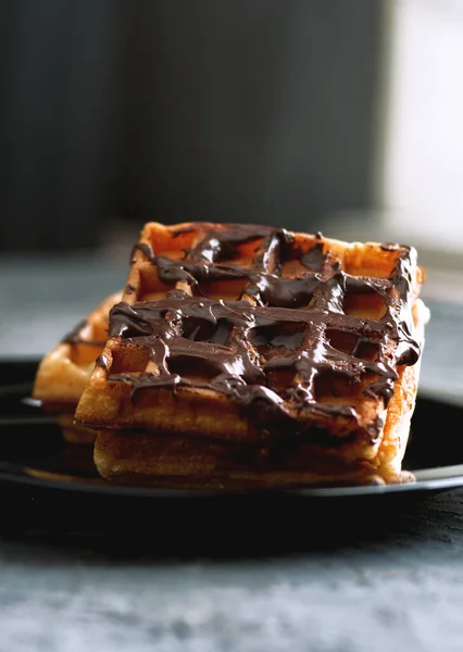 Siyah bir tabakta çikolatalı waffle.