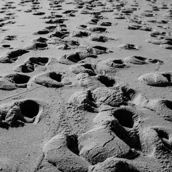 Pegadas na areia cinzenta da praia — Fotografia de Stock