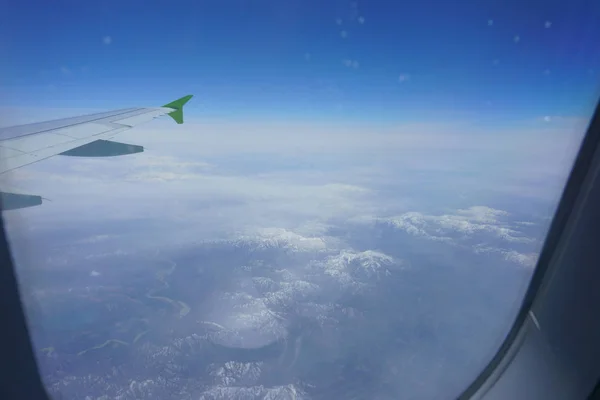 飛行機の窓から見る雪の山 — ストック写真