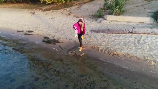 河边有个小孩的年轻妈妈 让纸船下水 和孩子一起散步 — 图库视频影像
