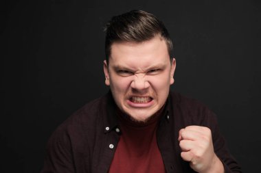 Gri arka planda izole edilmiş öfkeli genç adam portresi