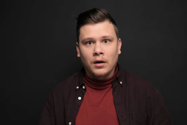 Portrait of young scared man isolated on gray background