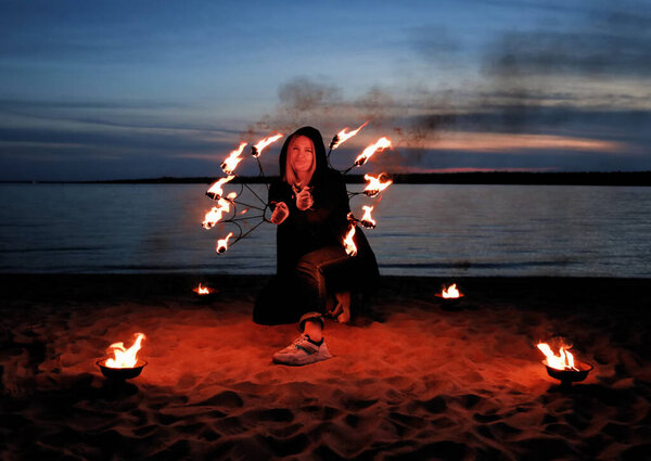 young girl by the sea shows a show with fire. details for working with fire. work with fire in nature.