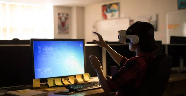 Executivo usando fones de ouvido de realidade virtual enquanto trabalhava na mesa no escritório — Fotografia de Stock