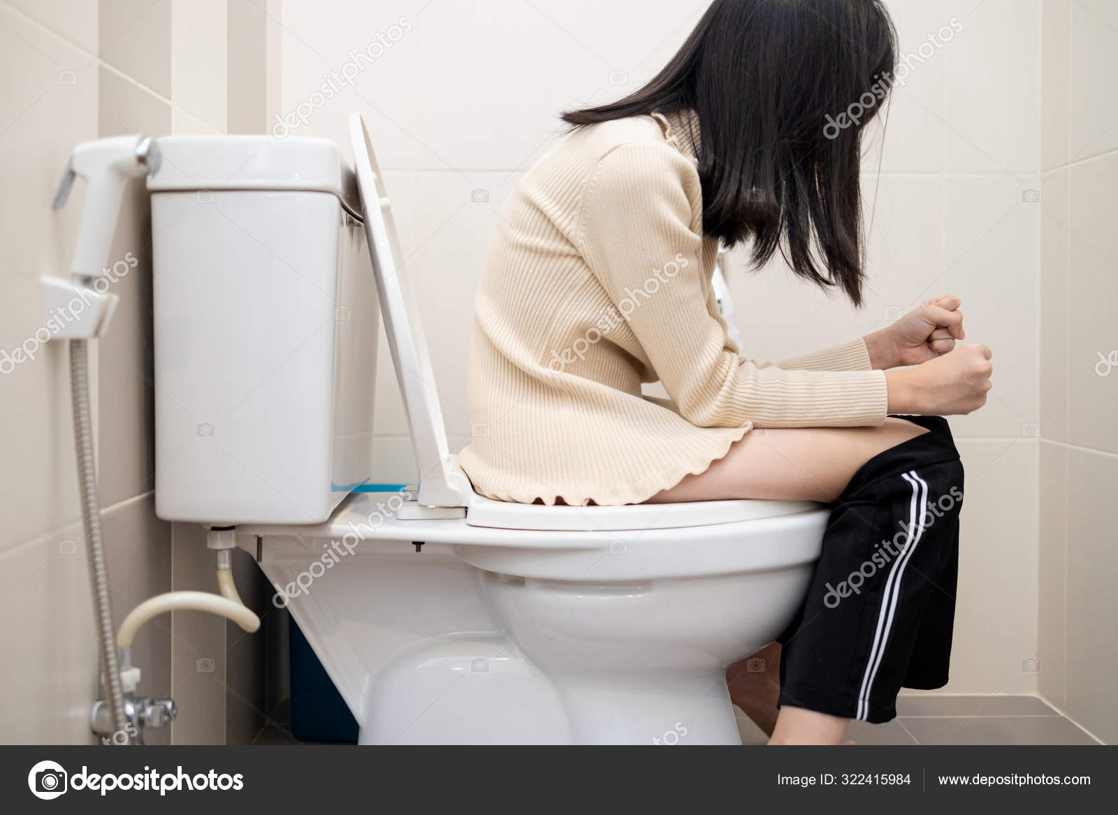 便秘　女 アジアの子供の女の子は、便秘、下痢や痔に苦しんでバスルームで彼女のズボンをトイレに座って、ストレスを受けた女性は痛みを伴う胃を感じる、ウンコを得ることができませんでしたアウト、医療  — ストック写真 © Chai2523 #322415984