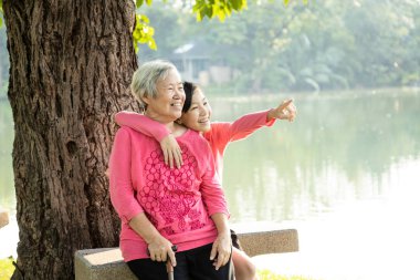 Mutlu yaşlı kadın ve çocuk gülüyor, açık hava parkında kucaklaşıyor, büyük anneanneyi seviyor, gülümseyen ergen torunun keyfini çıkarıyor, tatilde birlikte rahatlıyor, sağlık hizmetleri, nesil, yaşam tarzı. 