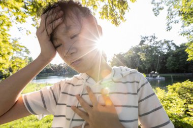 Tired asian woman suffer from sunburn very hot in summer weather problem feel faint,dizzy,difficulty breathing,female teenage with heat stroke,high temperature,burning heat wave hot sun on sunny day clipart