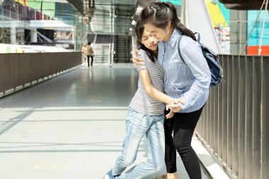 Asyalı bir anne kızına destek olurken genç kızı baygın, güneş çarpması geçiren yorgun bir kız çocuğu, güneşli bir günde açık havada çok sıcak güneş yanığı yüzünden acı çekiyor.