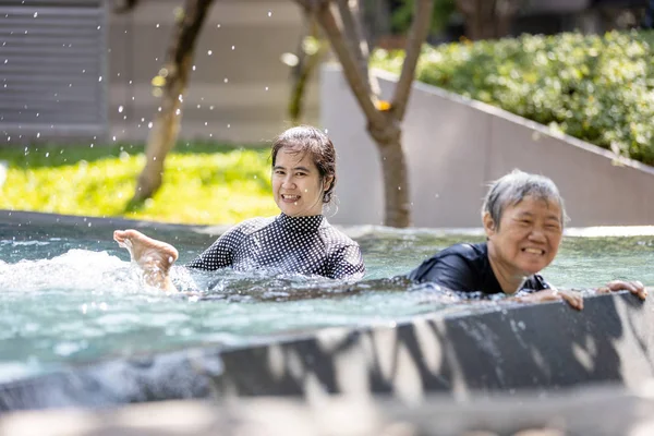 Happy asian senior people and young woman having fun, enjoy together in swimming pool, healthy elderly mother exercise, learn to swim in pool with smile trainer or daughter, health care concept — Stock fotografie