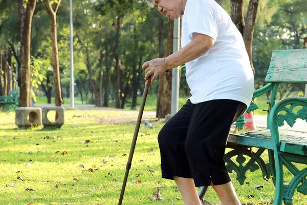 Несчастная старшая азиатка, страдающая геморроем, пожилая женщина боится боли в ягодицах от геморроя, осторожно сидит на скамейке в парке, чувствует себя внизу от боли, проблемы со здоровьем — стоковое фото