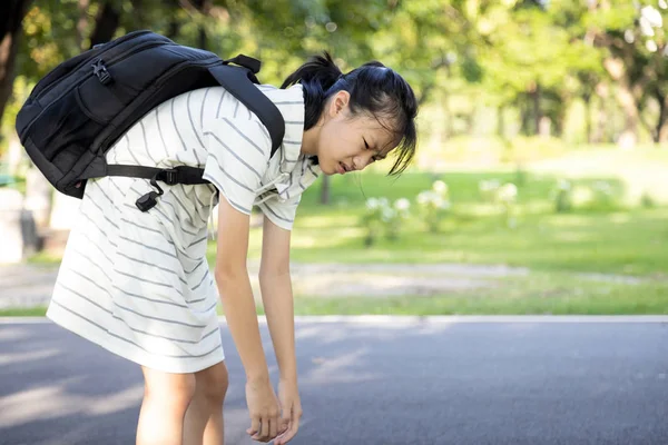 ストレスアジアの子供の女の子の重い学校の袋やバックパックを運ぶ、女性の十代の若者の背中に痛みを感じ、彼女の背中に本の完全な、学校には初めて行く、疲れて学生に戻る学校学習に — ストック写真