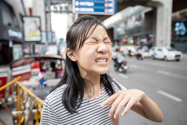 Asiatique enfant fille avec une sensation de brûlure, irritation des yeux de la fumée de voiture dans la ville, sentir la douleur des yeux, la poussière, allergie oculaire avec les yeux fermés effet de la pollution de l'air, adolescent dans la rue dans des environnements toxiques — Photo