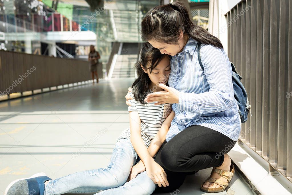 Asian mother help her daughter support while her teen daughter fainted unconscious while walking outside,tired child girl with heat stroke on a sunny day suffer from sunburn very hot in summer outdoor