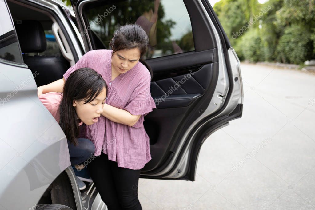 Asian child girl about to throw up from car sick or indigestion ,female teenage vomiting in a car suffers from motion sickness,daughter feeling dizzy from carsick,mother helping,care her,health care