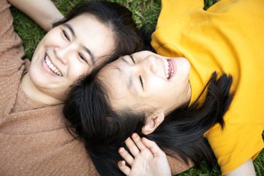 Top view, Happy family, Happy family, Asyalı anne ve güzel genç kız birlikte çimenlerde uzanmış, birlikte gülüyor yeşil doğa parkında gülümseyen Asyalı kız çocuğu, yaz tatili, aile hayatı.
