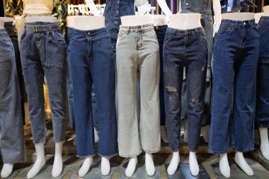 Çeşitli türde kot pantolon koleksiyonu, farklı renkte kadın pantolonları, farklı renklerde kot pantolonlar, reklam pantolonları mağazası, mankenlere asılı kot pantolonlar, sıra sıra pantolon.