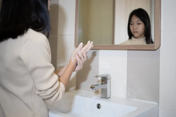 Азійська дівчинка, яка миє руки з милом на раковині у ванній кімнаті, дівчина - підліток з миттям рук після екскреції, знижує забруднення мікробів, миє руки, веде життя і дотримується концепції гігієни. — стокове фото