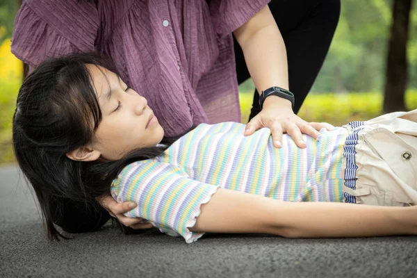 生病的女儿在玩耍和锻炼的时候晕倒在地板上，亚洲妈妈帮忙，照顾，患有充血性心力衰竭的小女孩，女性潜意识倒在地上，心脏病发作 — 图库照片