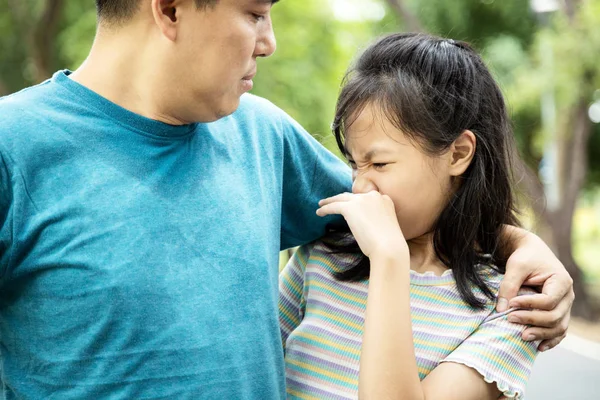 Foul-smelling man was hugging her daughter while her child  girl can smell the armpit smelly or the body odor foul from her father with closing her nose,feel stinks,asian male sweat from hot weather — Stockfoto
