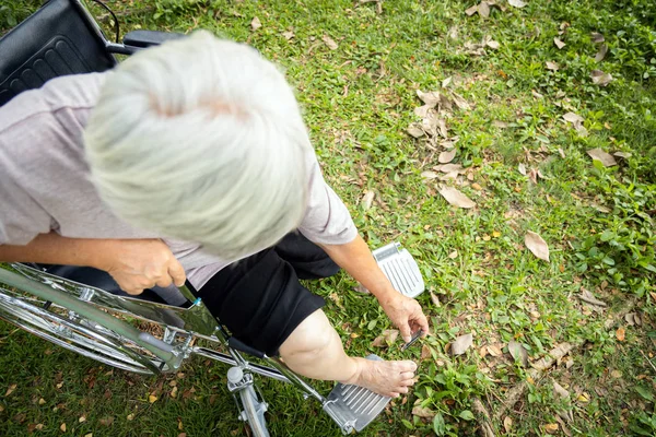 Asian senior woman hand hold nail clippers,female elderly people try to reach toenails,but can not to do this,knee and leg is very tight,makes it impossible to reach or bend down to trimmer the nails — 스톡 사진