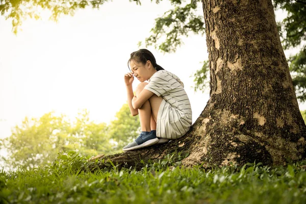 Gestresst aziatisch kind meisje zat alleen te huilen onder de boom in het park, wanhopige vrouwelijke tiener met depressieve symptomen verdrietig treuren lijden aan angst, depressie ziekte concept — Stockfoto