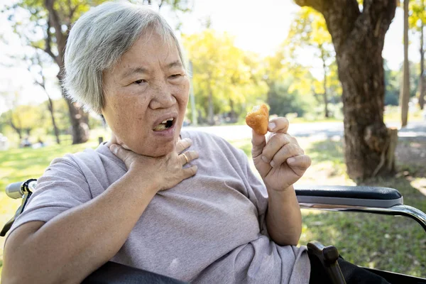 Asiatisk eldre kvinne som lider av kvelning og hoste, tette matvaner, eldre mennesker som kveles under fôring, mat som kan sitte fast i halsen og kveles med kuttskader, asfyksi, kvelningskonsept , – stockfoto