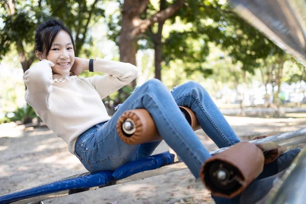 Krásná asijské dítě dívka cvičit fitness, dělat sit up cvičení pro zdraví a sílu při návštěvě městského parku, šťastný usmívající se žena dospívající dělá břišní sedy v venkovní tělocvičně, zdravotní péče — Stock fotografie