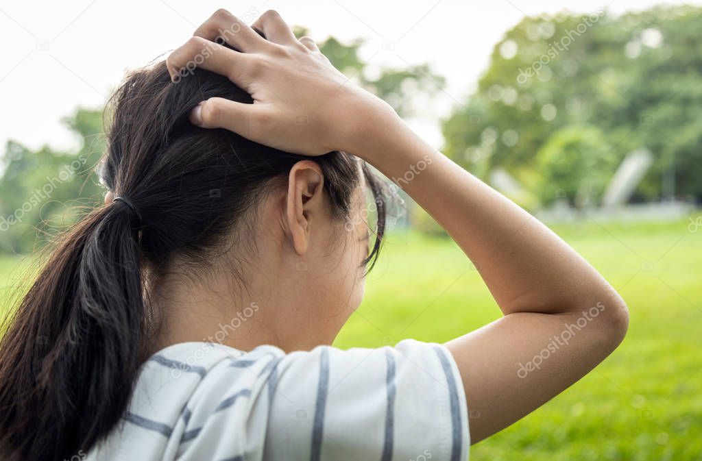 Sick asian child girl holding her painful head, brain cancer,hemorrhagic stroke and tumor inside brain,female teenage person with a severe headache in outdoor park,health problem , health care concept