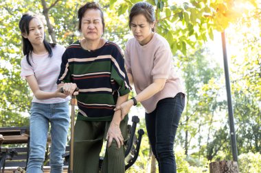 Eklem iltihabı, osteoartrit, kas ağrısı ya da miyozit olan Asyalı son sınıf öğrencisi bir kadın, yaşlı insanlar dizlerinden el ele tutuşuyor, dizlerinde ağrı hissediyor, şişmiş, ayaktayken bacak yaralanması, sağlık sorunları var.