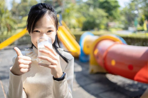 Sorridente asiatico adolescente ragazza bere un bicchiere di latte, godendo di un — Foto Stock