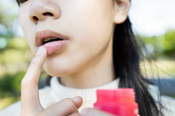 Asiática niña mantiene sus labios, cuidado de la piel, belleza y protec — Foto de Stock