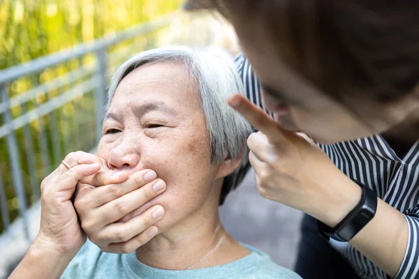 Angry asian woman covering senior mouth and showing silence gesture, keep a secret be quiet,social violence,aggression, scared elderly people with female caregiver,bad relationship,physical abuse — 스톡 사진