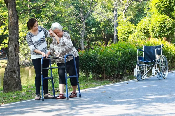 Літня жінка азіатського походження під час реабілітації після операції на коліні, молода доглядальниця, яка заспокоює літніх людей, які займаються ходьбою з відчуттям втоми, доглядальницею, турботою, підтримкою. — стокове фото