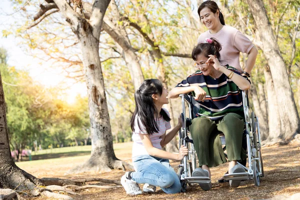 Happy asian family,daughter,granddaughter miss and visit her  senior mother at nursing home in holiday,adult woman,teen girl enjoy with elderly people in wheelchair having fun, talk,laughing together