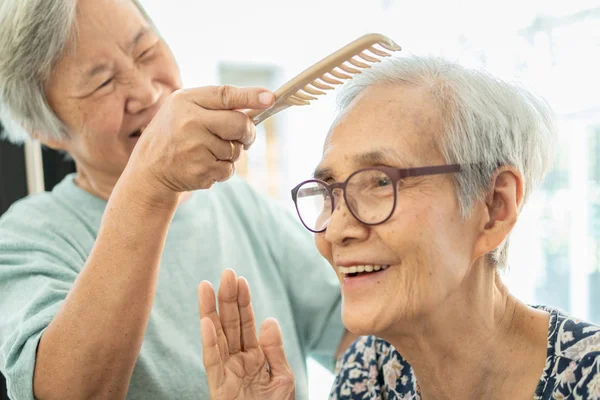 Feliz asiática anciana, mujer mayor peinando el pelo a amigo mayor mujer en el hogar de ancianos, sonriendo ancianos o hermana de cuidado, apoyo, hablar, buen tiempo juntos, enérgicamente, amistad de la edad de jubilación —  Fotos de Stock